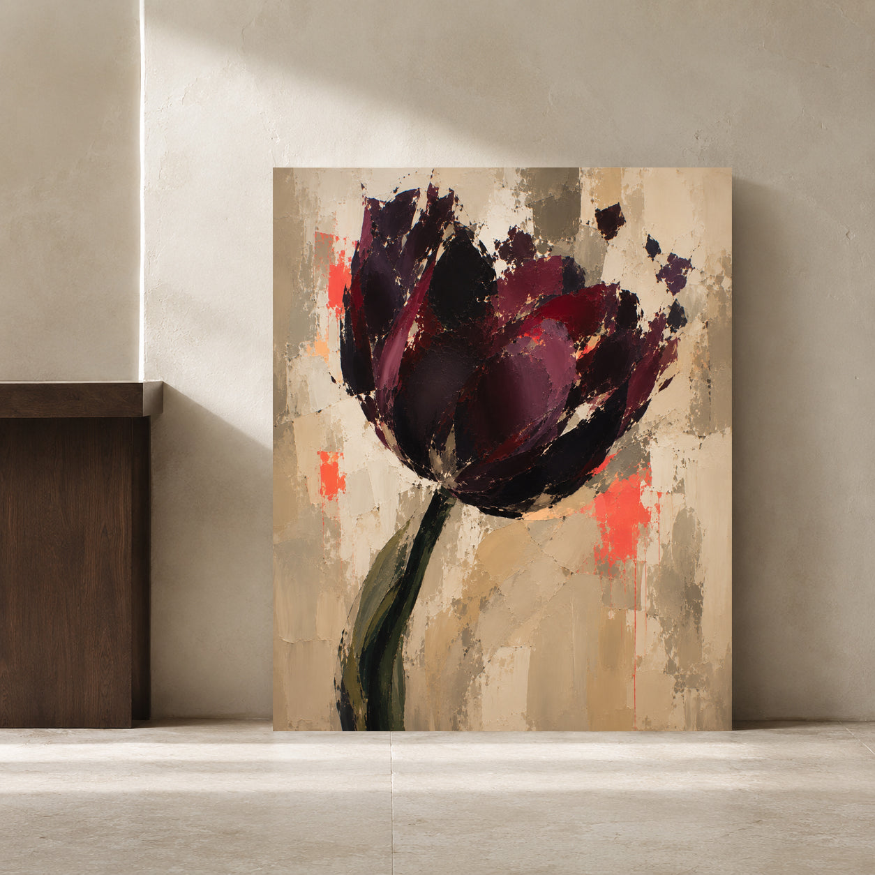 Abstract floral wall art leaning against a textured beige wall in a minimalist interior setting. The artwork depicts a large dark plum and burgundy flower with a green stem on a warm beige and gray background with coral accents.