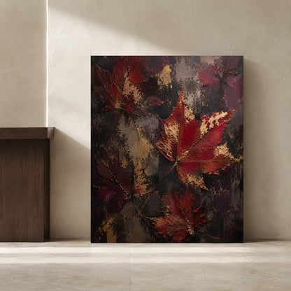 A square canvas painting leaning against a textured beige plaster wall on a concrete floor. The artwork features textured, impasto-style red and burgundy autumn leaves layered over a dark, metallic charcoal and gold background.
