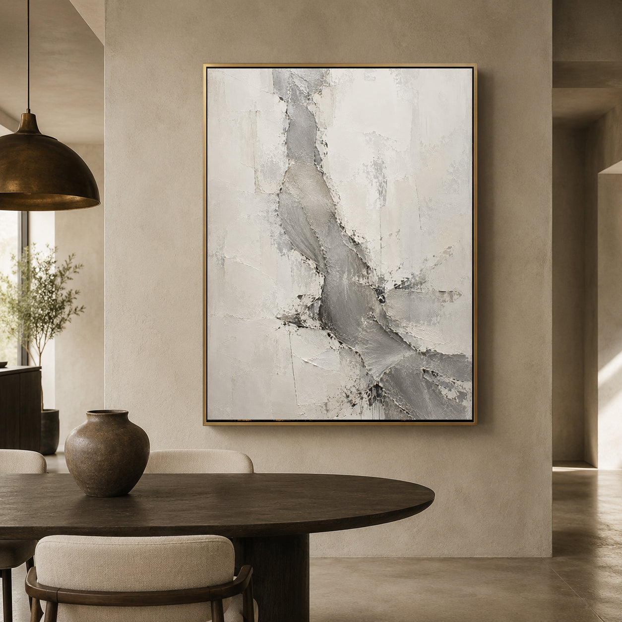 A large framed abstract canvas print with gray and white textured brushstrokes hangs on a beige plaster wall above a dark wood dining table in a modern, minimalist interior.