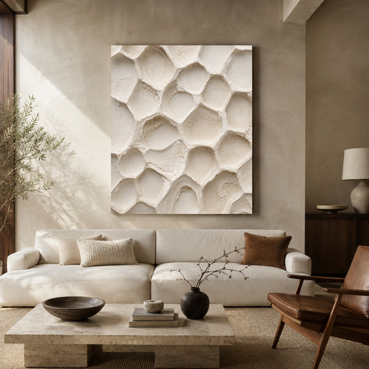Large square canvas wall art featuring a textured organic pattern in warm off-white and beige, displayed above a cream sofa in a modern, neutral-toned living room.