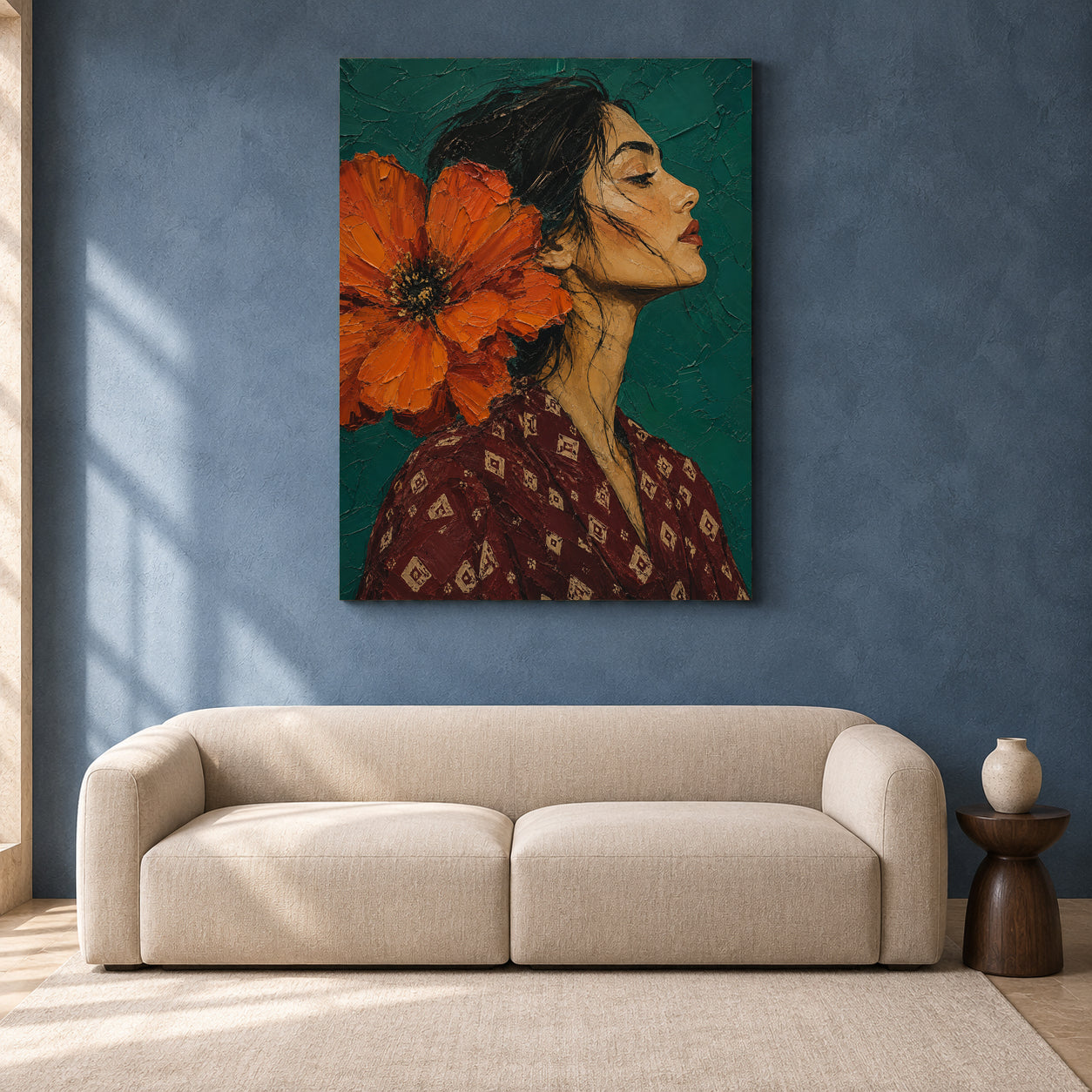 A vertical canvas art print depicting a woman in profile with a large orange flower on her head, hanging on a textured blue wall above a modern beige sofa in a styled living room.