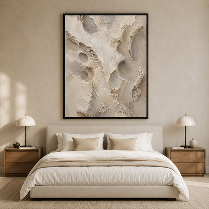 A large framed abstract wall art print with textured beige, cream, and gray brushstrokes hangs above a neatly made bed in a minimalist, warm-toned bedroom.