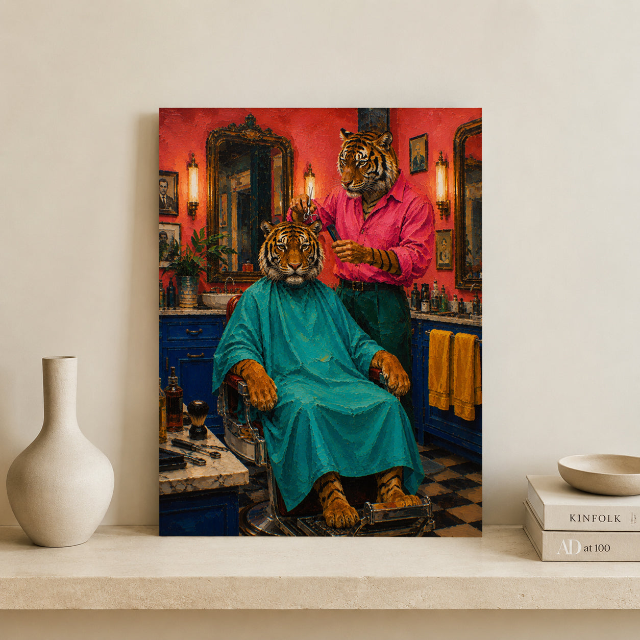 A vertical canvas wall art print depicting a whimsical barbershop scene with tiger-headed characters, styled leaning against a wall on a shelf next to a white ceramic vase and books.