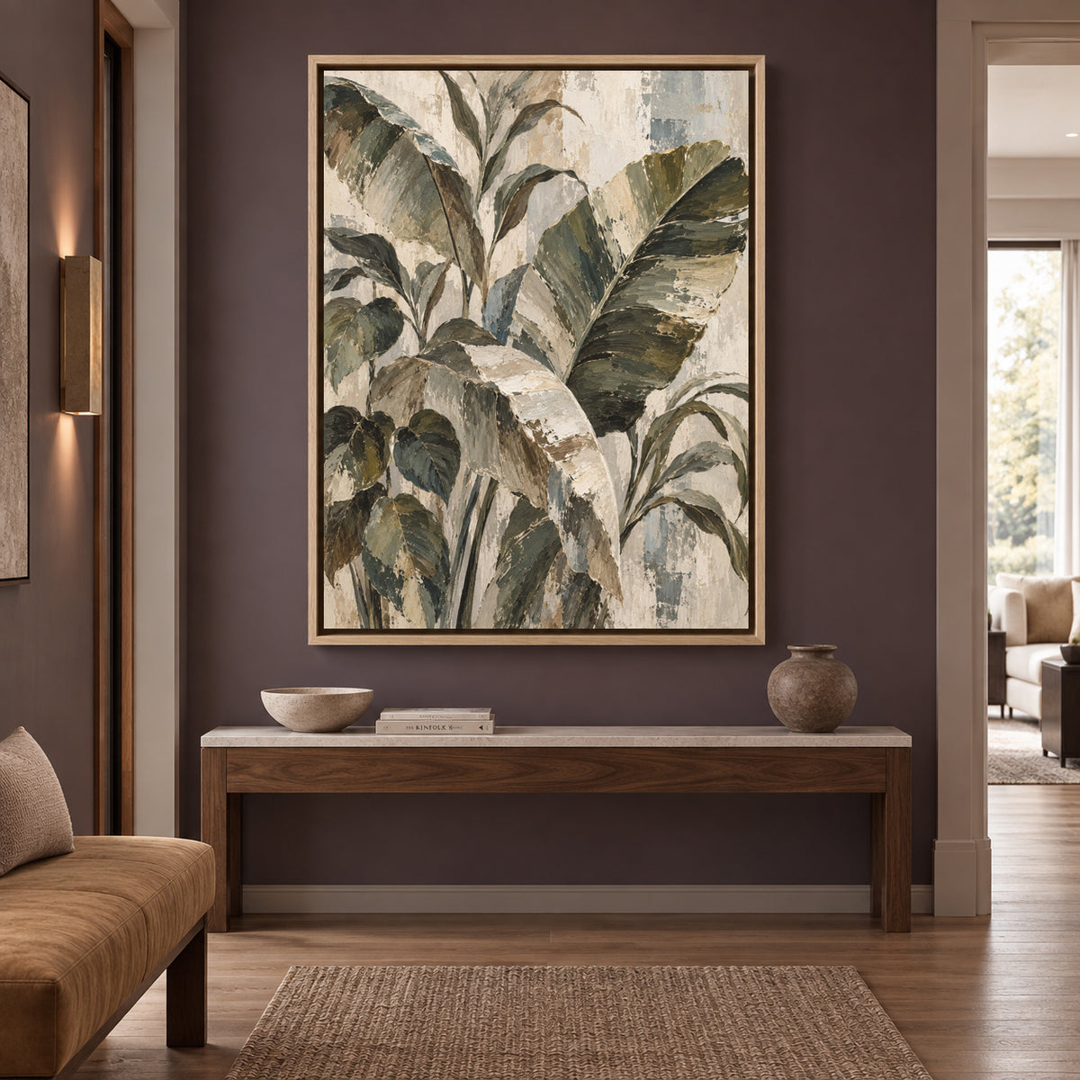 A framed botanical wall art print featuring large green and beige leaves, displayed in a modern living room setting above a wooden console table.