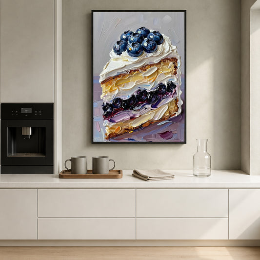 A framed vertical canvas print of a blueberry cake slice hangs on a beige wall above a white kitchen counter with mugs, a glass bottle, and a coffee machine.