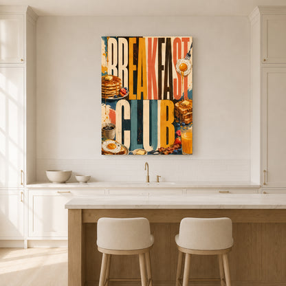 A colorful canvas wall art print featuring the words 'BREAKFAST CLUB' with breakfast food illustrations, hanging on a white kitchen wall above a counter with two stools.
