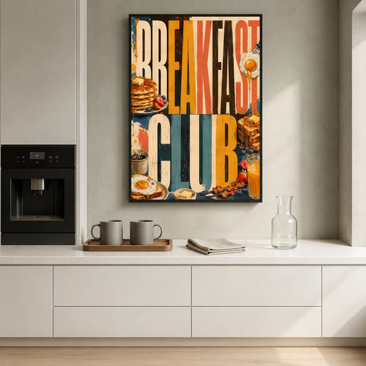 A framed vertical wall art print with a colorful collage-style breakfast theme hangs on a light gray kitchen wall above a white countertop. The print features large text reading 'BREAKFAST CLUB' with pancakes, eggs, toast, and other breakfast imagery.