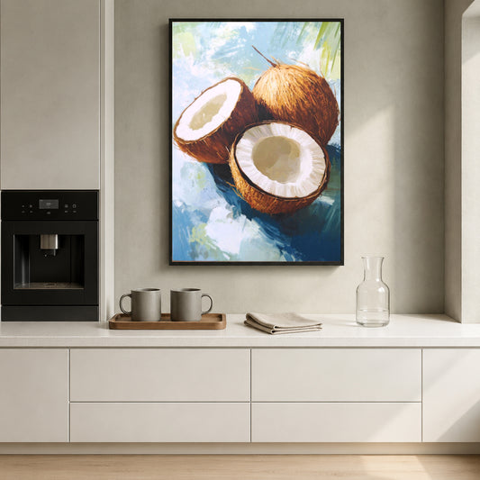 A framed vertical canvas print of a painted coconut still life hangs on a light beige wall above a white kitchen counter with mugs, a glass bottle, and an espresso machine.