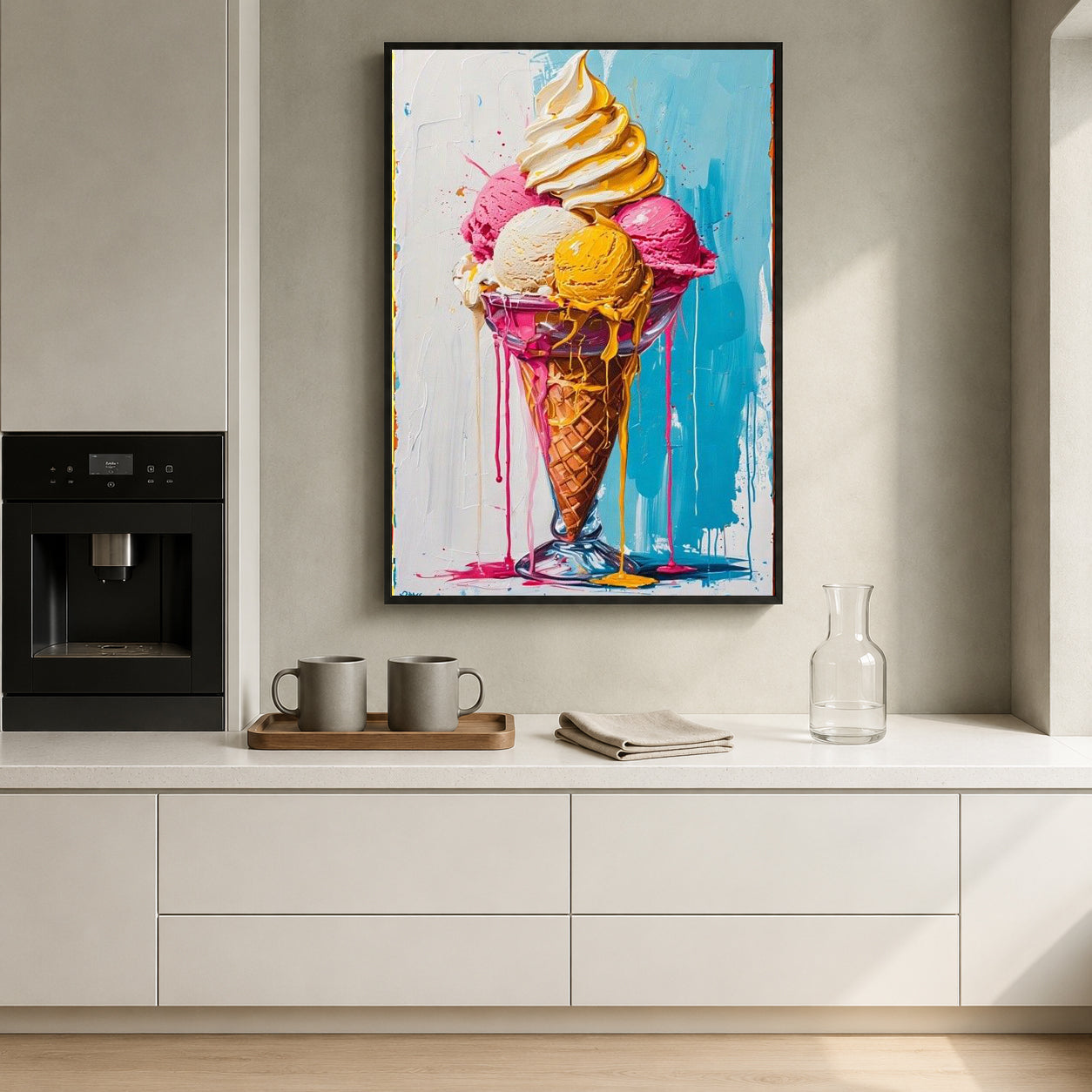 A framed vertical canvas print of a colorful ice cream cone painting hanging on a light gray wall above a white kitchen counter with mugs and a glass carafe.