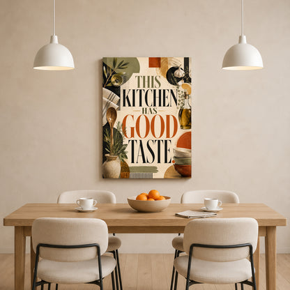 A vertical canvas wall art print with the text 'THIS KITCHEN HAS GOOD TASTE' in large black and orange lettering, surrounded by kitchen-themed illustrations, hanging on a beige wall above a wooden dining table with four chairs and two hanging pendant lights.