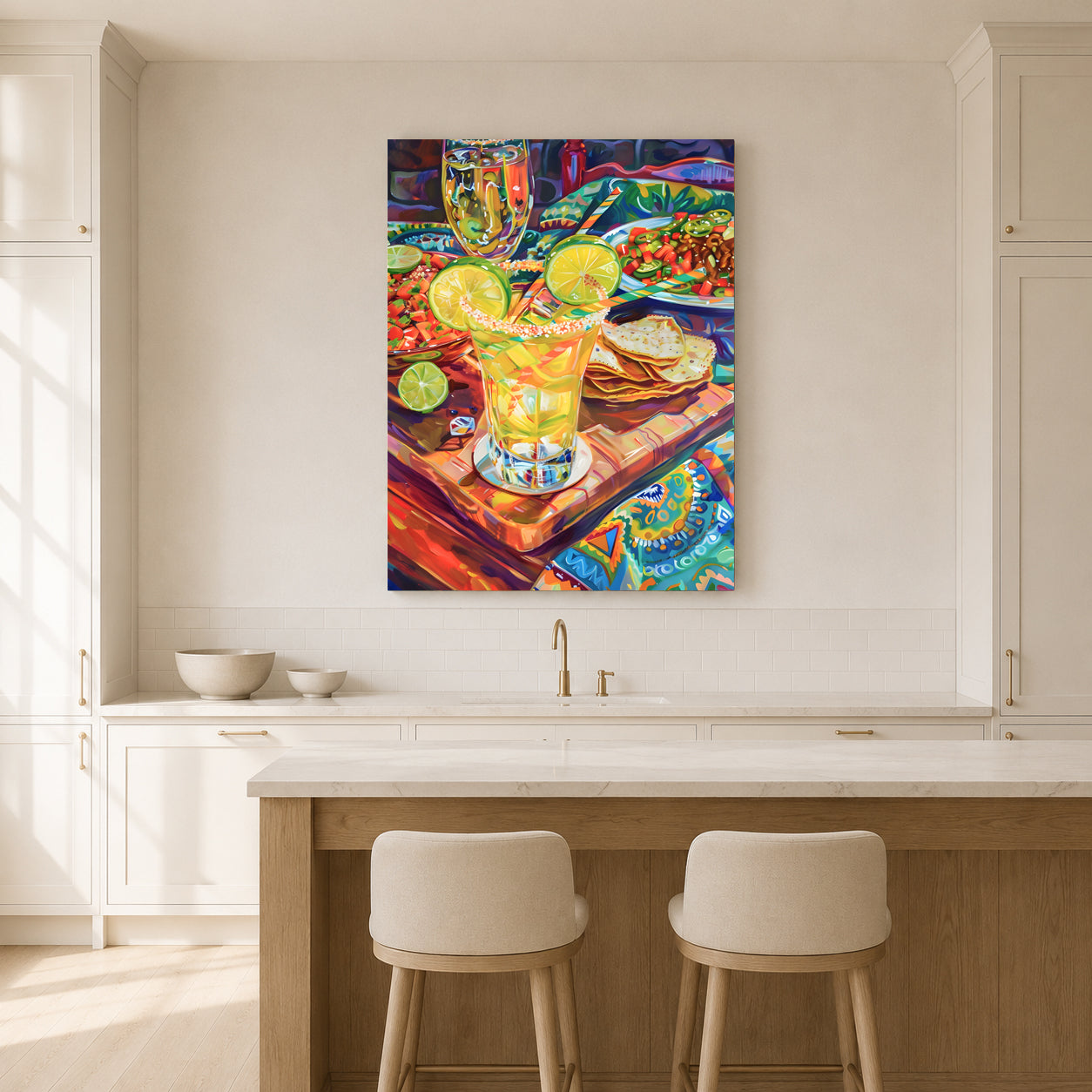 A colorful canvas wall art print depicting a vibrant kitchen scene with a margarita glass, displayed on a beige wall above a white kitchen island with two stools.