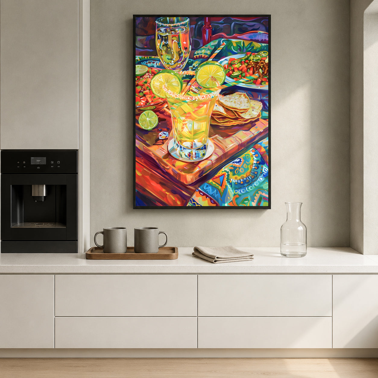 A colorful framed art print depicting a vibrant still life of margarita glasses, limes, and tortilla chips, displayed on a light gray wall in a modern kitchen setting.