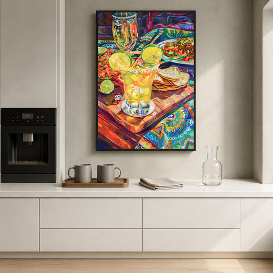 A colorful framed art print depicting a vibrant still life of margarita glasses, limes, and tortilla chips, displayed on a light gray wall in a modern kitchen setting.