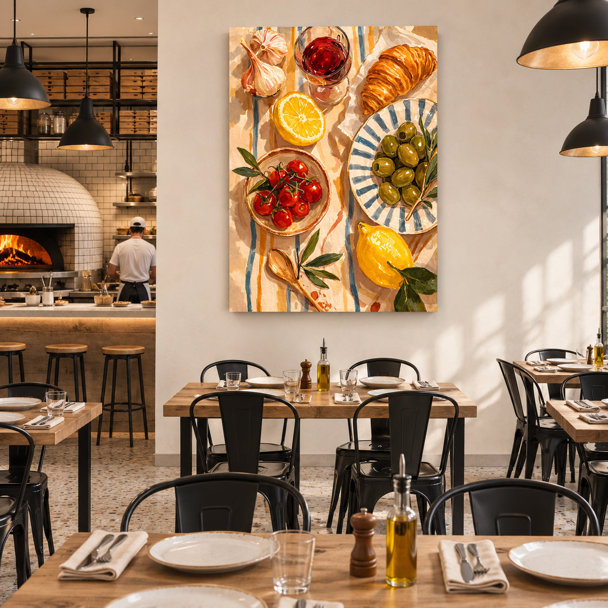 A vertical canvas wall art print depicting a colorful Mediterranean breakfast spread with croissants, lemons, tomatoes, olives, and garlic, displayed on a white wall in a modern restaurant setting.