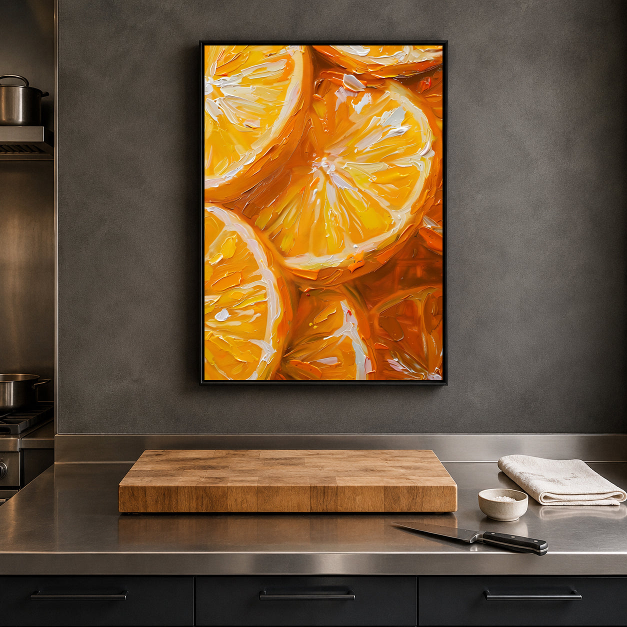 A framed vertical canvas print featuring an oil painting of vibrant orange slices, displayed on a dark gray textured wall above a kitchen counter with a wooden cutting board, knife, and small bowl.