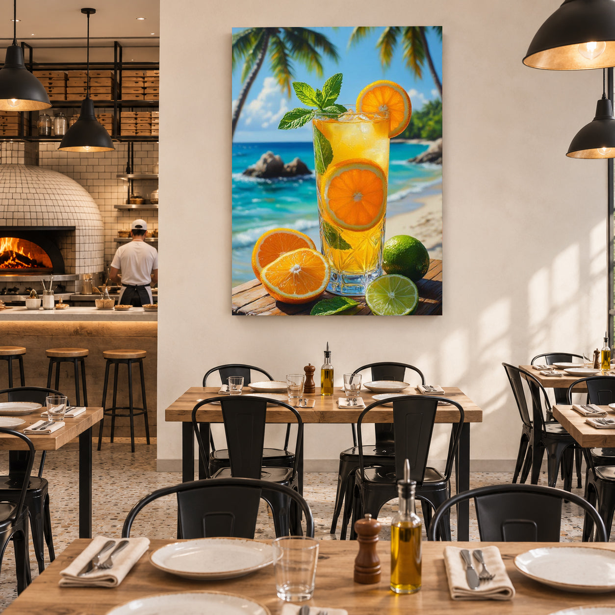 A large vertical canvas wall art print featuring a tropical beach scene with a glass of orange juice, oranges, limes, and palm trees, displayed on a white wall in a modern restaurant setting.