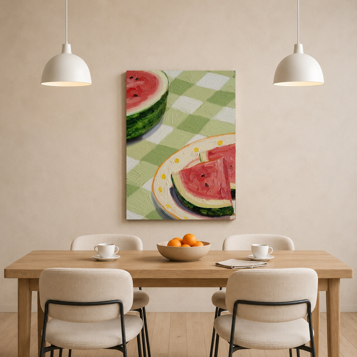 A vertical canvas wall art print depicting watermelon slices on a green and white checkered tablecloth, hanging on a beige wall above a wooden dining table with four chairs and two white pendant lights.